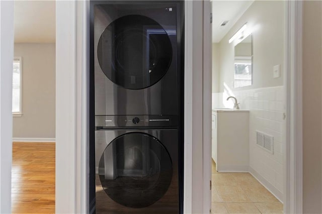 laundry area featuring light tile patterned floors, visible vents, laundry area, and stacked washer / dryer