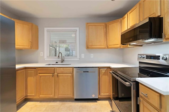 kitchen featuring light countertops, appliances with stainless steel finishes, light brown cabinetry, and a sink