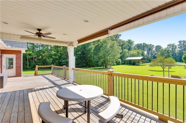 wooden terrace with ceiling fan, a lawn, and a gazebo