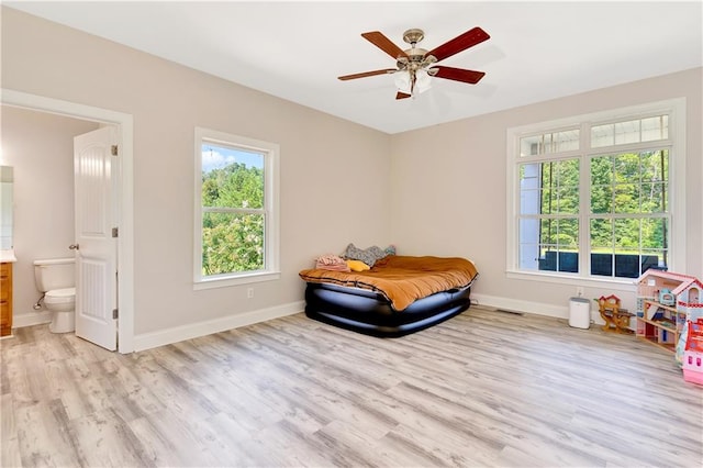 bedroom featuring connected bathroom, light wood-type flooring, and ceiling fan