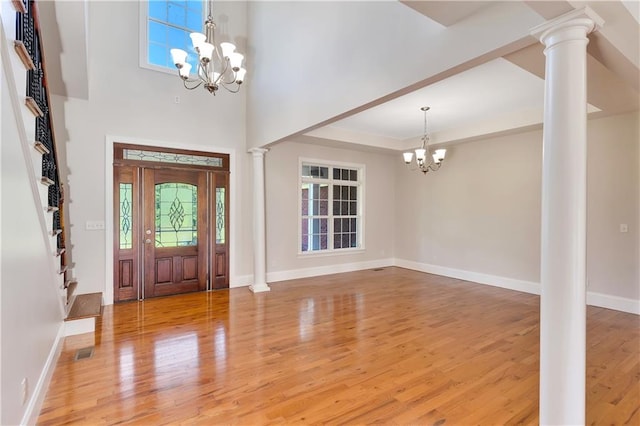 entrance foyer featuring an inviting chandelier, decorative columns, and hardwood / wood-style floors