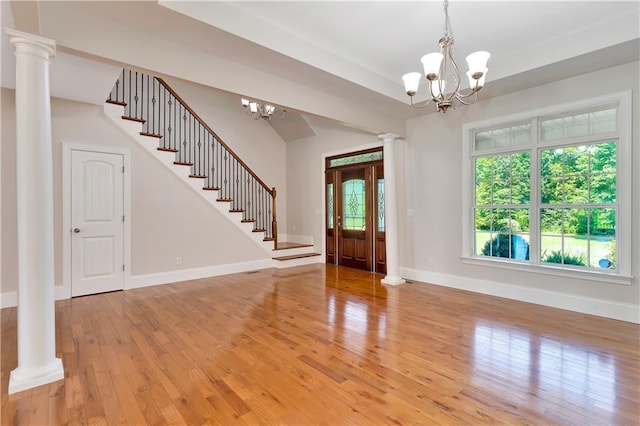 entrance foyer featuring decorative columns, light hardwood / wood-style flooring, and a notable chandelier