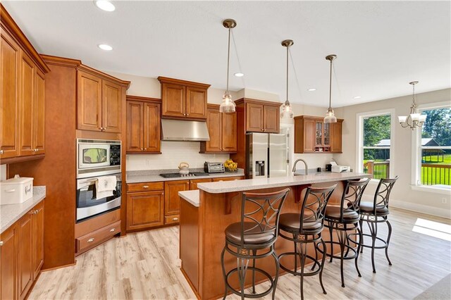 kitchen featuring a kitchen island with sink, light hardwood / wood-style flooring, a breakfast bar area, and stainless steel appliances