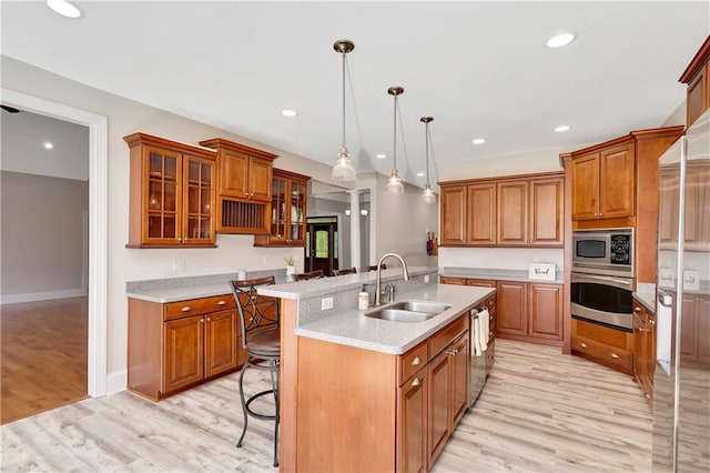 kitchen featuring decorative light fixtures, sink, a breakfast bar area, light hardwood / wood-style floors, and appliances with stainless steel finishes