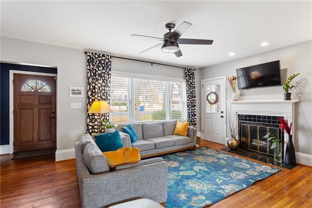 living room featuring a tiled fireplace, hardwood / wood-style flooring, and ceiling fan