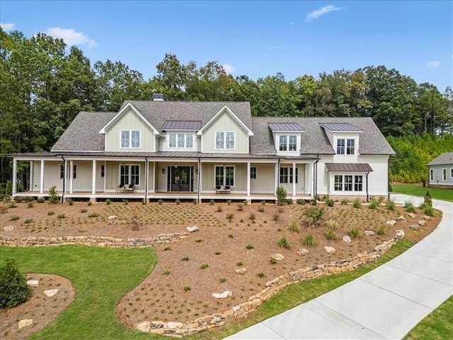 view of front of property with board and batten siding, a porch, a standing seam roof, and a front lawn