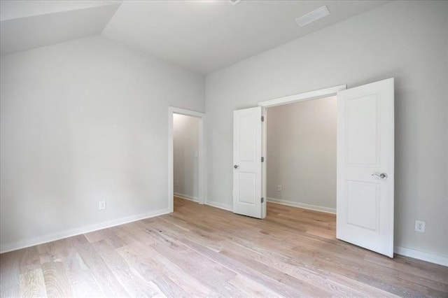 unfurnished bedroom featuring wood finished floors, vaulted ceiling, and baseboards