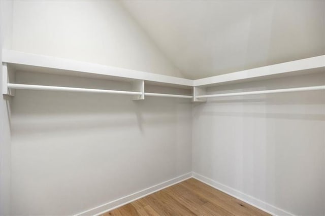 walk in closet with wood finished floors and lofted ceiling