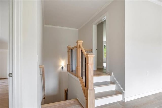 stairs featuring ornamental molding, wood finished floors, and baseboards