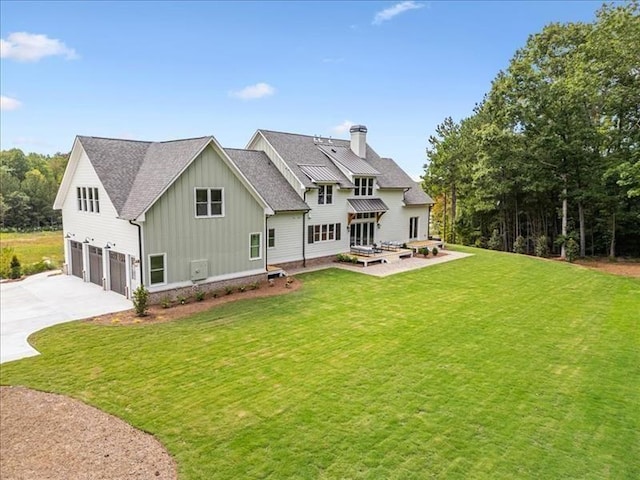 rear view of property with board and batten siding, a garage, concrete driveway, and a lawn