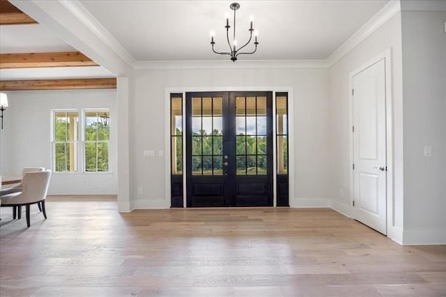 foyer entrance with a chandelier, wood finished floors, french doors, crown molding, and baseboards