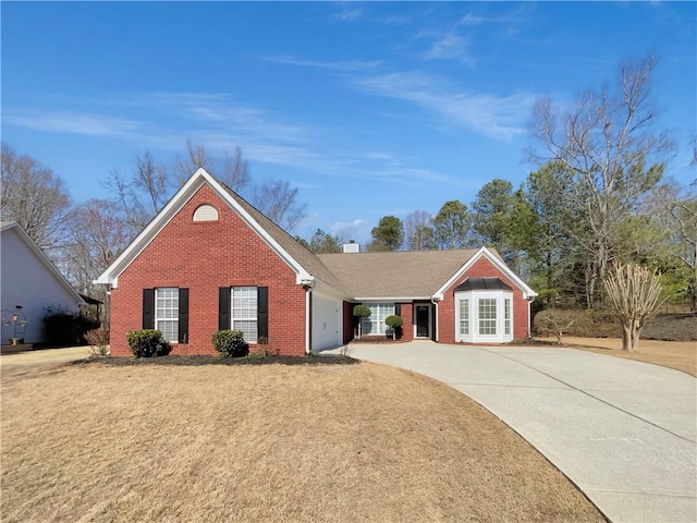 ranch-style house featuring brick siding, driveway, a chimney, and an attached garage