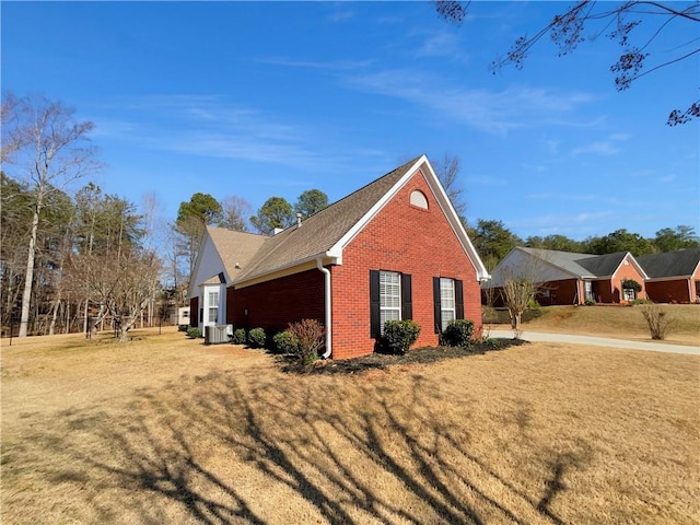 view of side of home featuring brick siding, a lawn, and central air condition unit