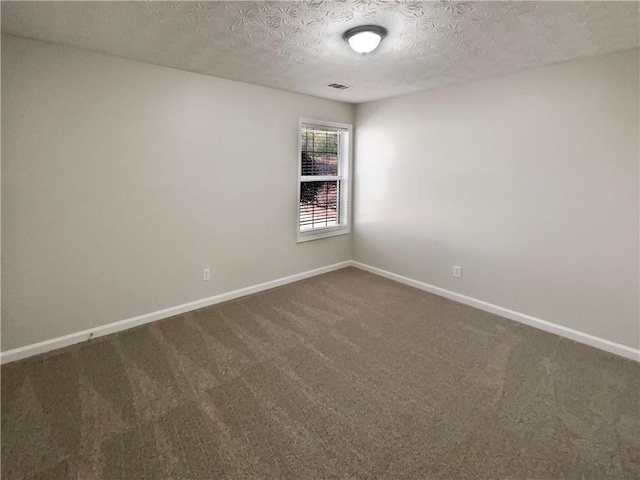 empty room with visible vents, baseboards, dark colored carpet, and a textured ceiling