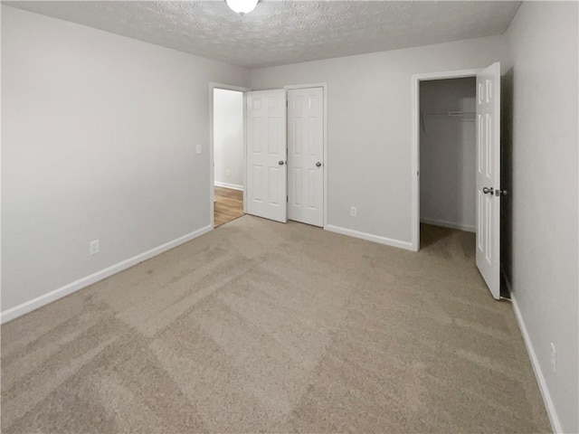 unfurnished bedroom with a textured ceiling, baseboards, and carpet flooring