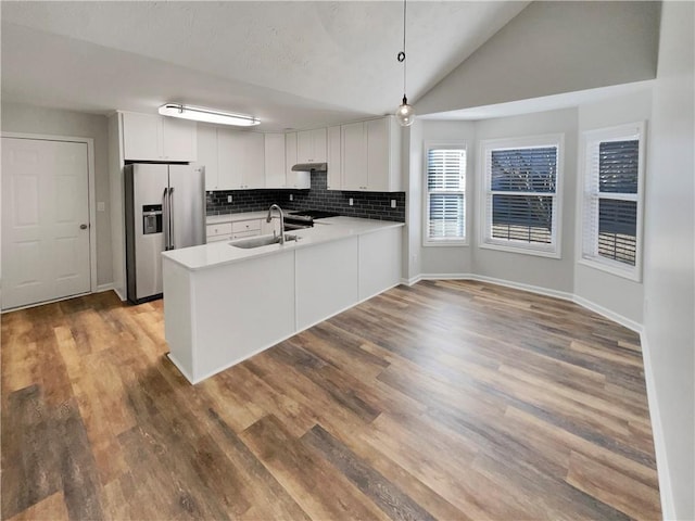 kitchen with tasteful backsplash, a sink, wood finished floors, stainless steel fridge, and a peninsula