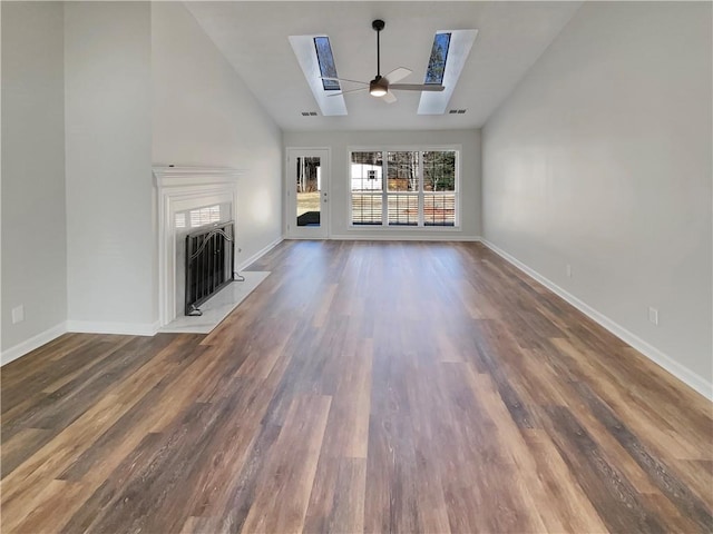 unfurnished living room with a skylight, a fireplace with flush hearth, baseboards, and wood finished floors