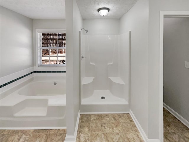 bathroom with a shower, a garden tub, a textured ceiling, and baseboards