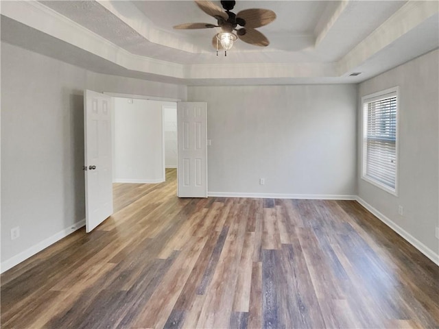 unfurnished room featuring wood finished floors, a raised ceiling, and baseboards