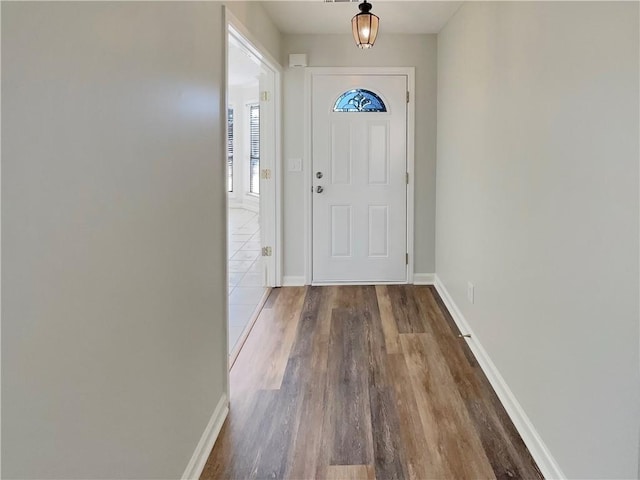 doorway to outside with baseboards and wood finished floors