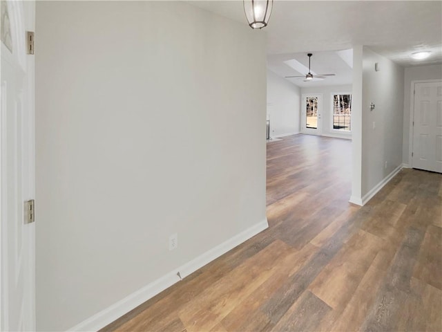 corridor with baseboards and wood finished floors