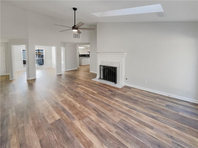 unfurnished living room featuring ceiling fan with notable chandelier, visible vents, a fireplace, and wood finished floors