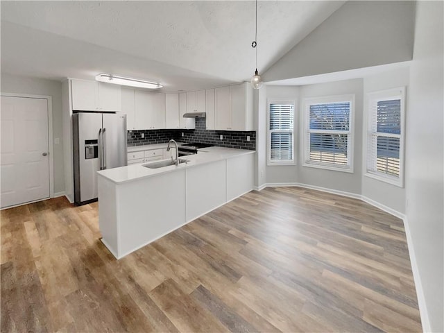 kitchen featuring appliances with stainless steel finishes, a peninsula, a sink, light countertops, and backsplash