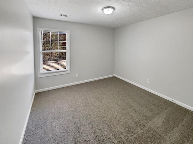 carpeted spare room featuring visible vents, a textured ceiling, and baseboards