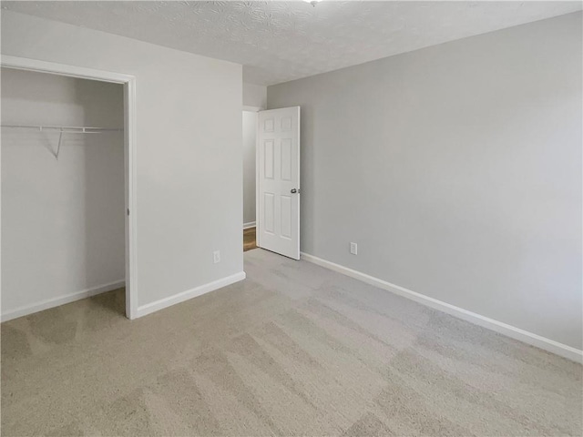 unfurnished bedroom with a textured ceiling, baseboards, a closet, and carpet flooring