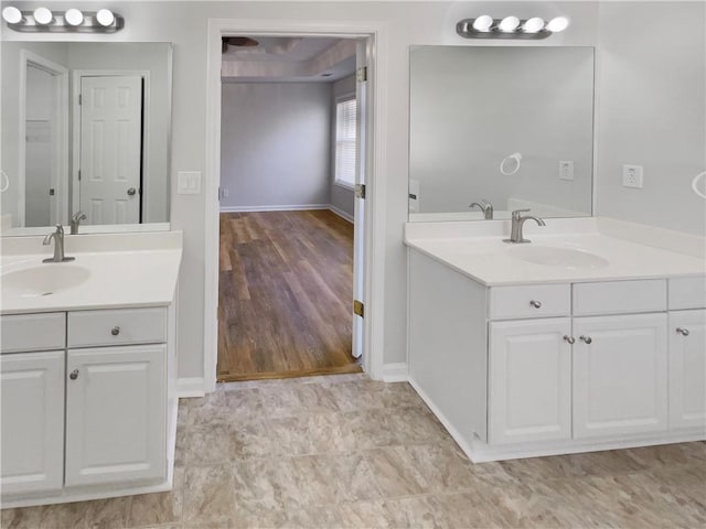 full bathroom featuring two vanities, a sink, and baseboards