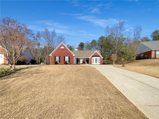 single story home featuring driveway, a chimney, and brick siding