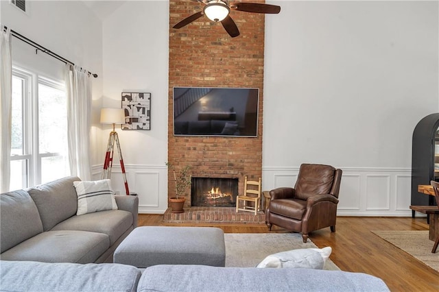 1867 N Creek Cir, Alpharetta, GA 30009 - living room featuring a fireplace, wood finished floors, ceiling fan, wainscoting, and a decorative wall