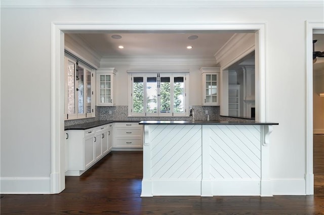 kitchen featuring dark countertops, backsplash, and glass insert cabinets