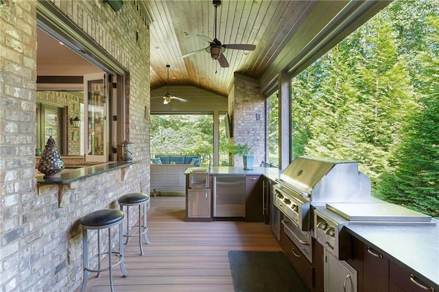 view of patio featuring ceiling fan, exterior kitchen, area for grilling, and a wooden deck