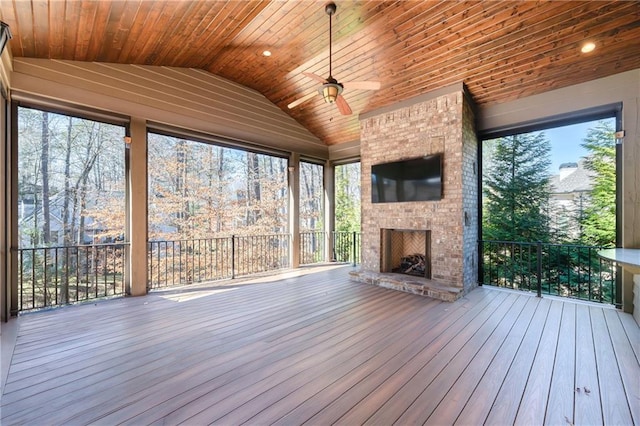 unfurnished sunroom featuring vaulted ceiling, a fireplace, wooden ceiling, and a ceiling fan