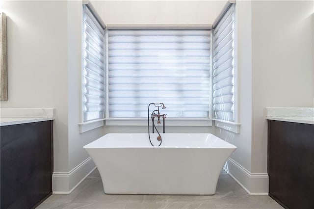 full bath featuring baseboards, a freestanding bath, and vanity