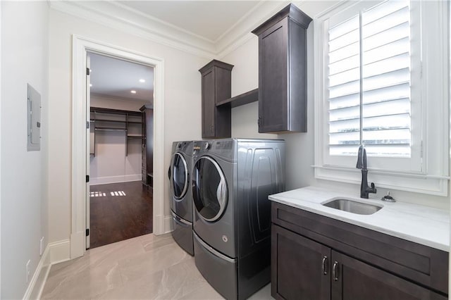 laundry room with cabinet space, baseboards, crown molding, separate washer and dryer, and a sink