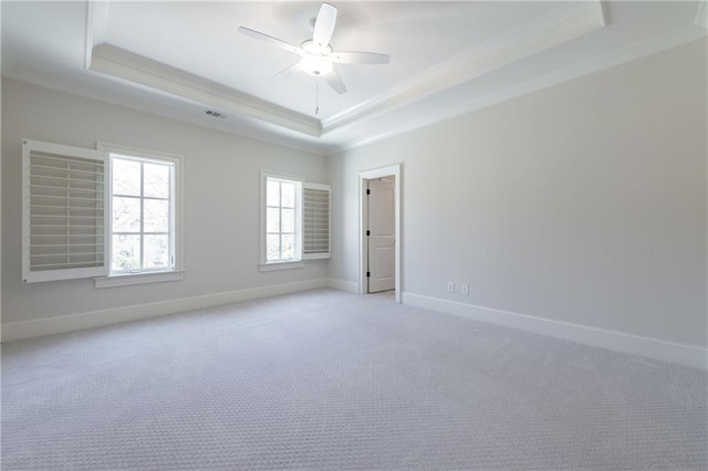 unfurnished room featuring a tray ceiling, ornamental molding, light carpet, ceiling fan, and baseboards