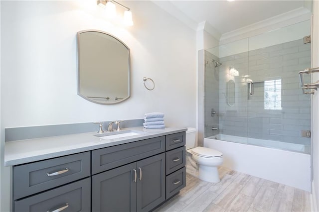 full bath with crown molding, toilet, wood tiled floor, combined bath / shower with glass door, and vanity