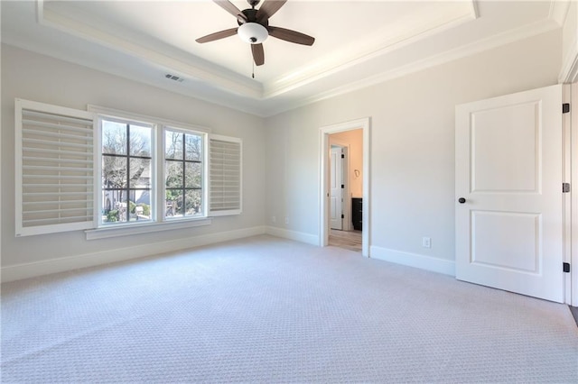 unfurnished bedroom featuring light carpet, visible vents, baseboards, a tray ceiling, and crown molding