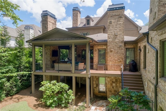 rear view of house with a deck, brick siding, a shingled roof, stairs, and a chimney