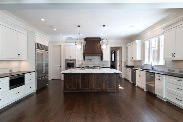 kitchen featuring dark wood finished floors, stainless steel appliances, custom range hood, ornamental molding, and a sink