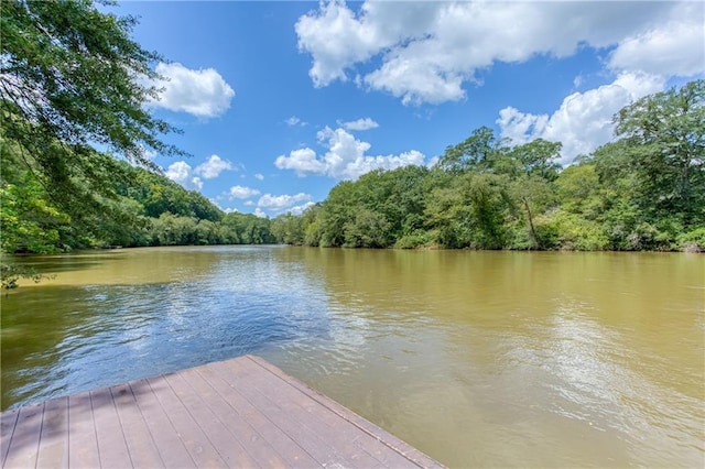 view of dock with a water view and a wooded view