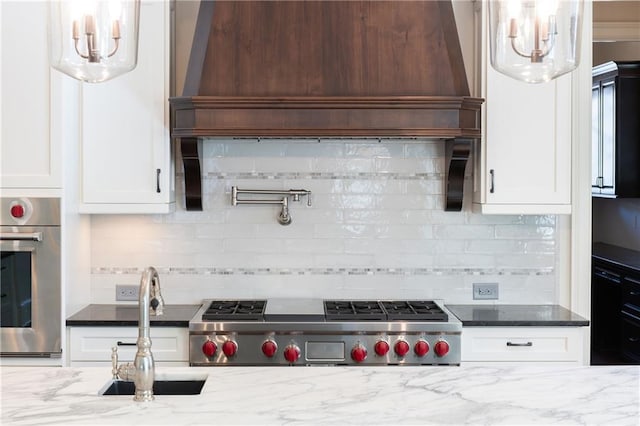 kitchen with dark stone counters, white cabinets, oven, and a sink