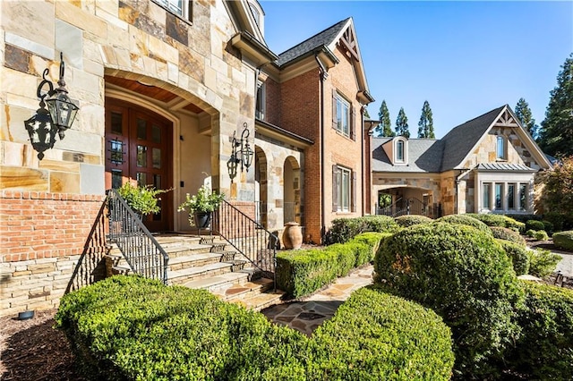 view of exterior entry with stone siding and brick siding