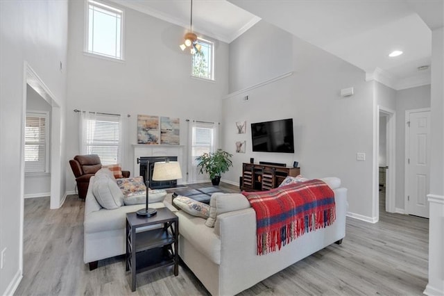 living room featuring light wood-type flooring, a high ceiling, and crown molding