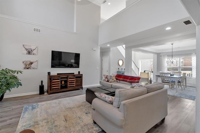 living room featuring a chandelier, a towering ceiling, and hardwood / wood-style floors