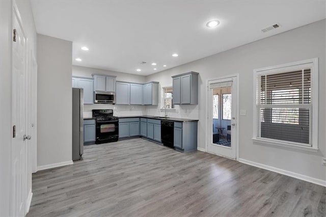 kitchen with light hardwood / wood-style floors, sink, black appliances, and gray cabinetry