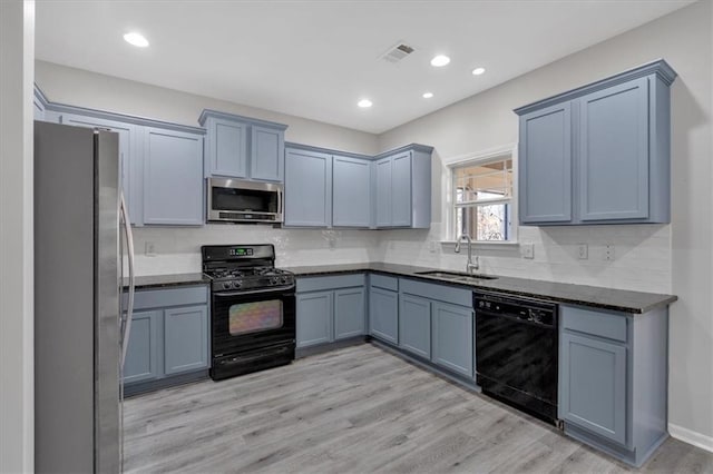 kitchen featuring light wood-type flooring, sink, black appliances, and tasteful backsplash