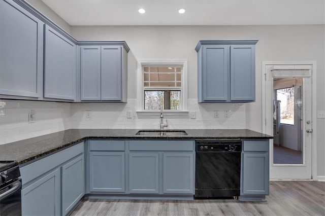 kitchen featuring dishwasher, light wood-type flooring, dark stone counters, sink, and electric range oven